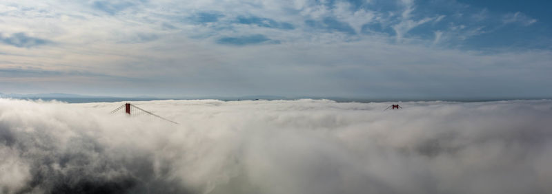 Low angle view of people on beach against cloudy sky