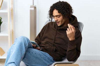 Young woman using phone while sitting on sofa at home