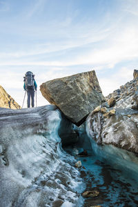 Rear view of people on rock against sky during winter