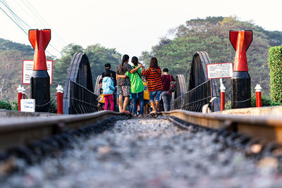 People standing on railroad track against sky