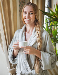 Portrait of a smiling young woman drinking coffee
