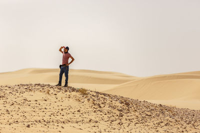 Man standing on sand dune in desert against sky