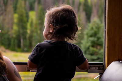 Rear view of girl looking through window