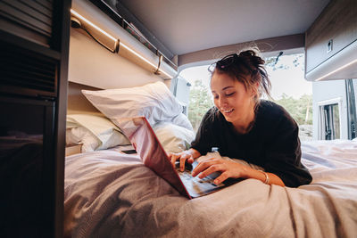 Young woman using laptop in camper