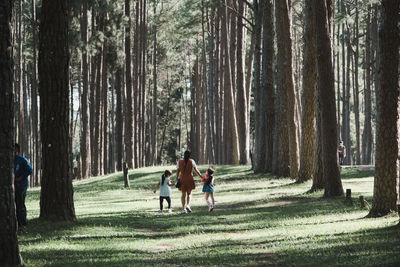 Rear view of mother and kids walking in forest