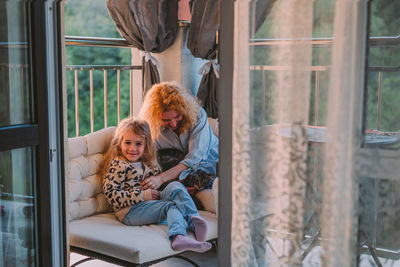 Happy child with smile plays on summer at home with mom, cat at sunset. cat, dog, pets family member