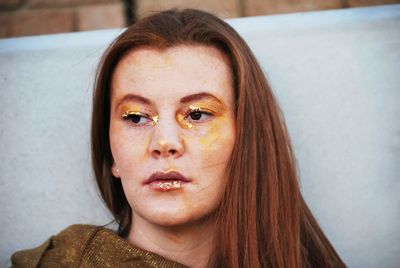 Close-up of thoughtful young woman looking away against wall