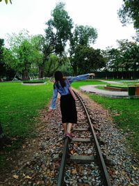 Rear view of woman walking on railroad track