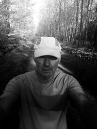 Portrait of man standing by plants in forest