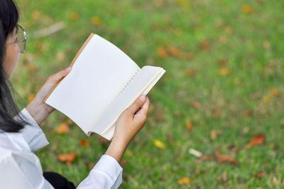 Midsection of woman reading book on field