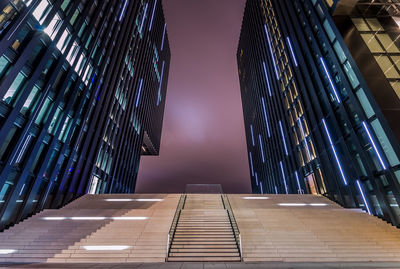 Low angle view of steps amidst buildings against sky at dusk