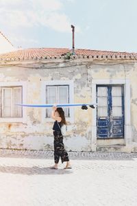 Full length side view of woman standing against building