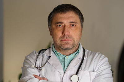 Portrait of mature doctor against wall