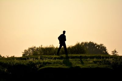 Silhouette man standing on field against sky during sunset