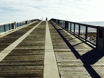 Pier on sea against cloudy sky