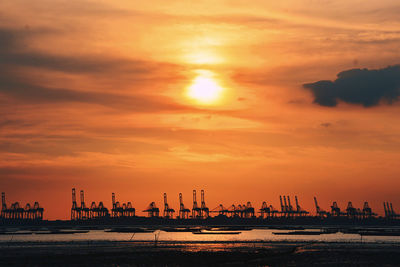 Silhouette bridge over sea against sky during sunset