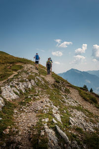 Rear view of people walking on mountain against sky