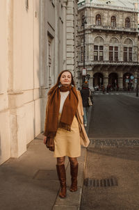 Full length portrait of woman standing against building in city