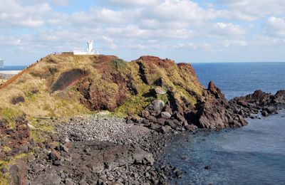 Scenic view of cliff by sea against sky