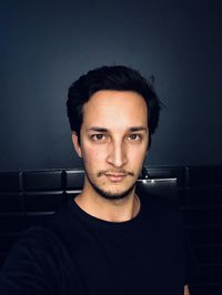 Portrait of young man standing against wall