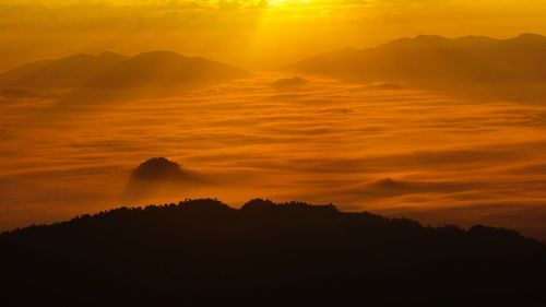 Scenic view of silhouette mountains against orange sky