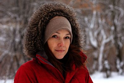 Portrait of  middle aged woman looking at camera in winter time in warm cloth with hood