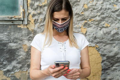 Midsection of woman holding mobile phone against wall