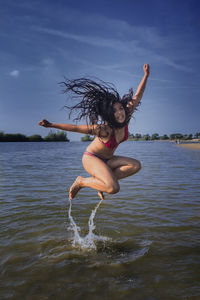 Boy jumping in water against sky