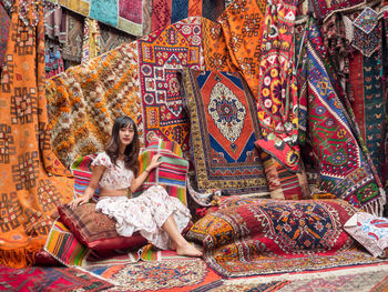 Portrait of woman sitting against carpets at market