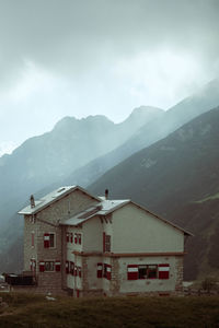 View of a mid-mountain alpine landscape with a hut for hiking against background of grass and stones