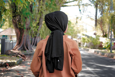 Rear view of woman standing on road in city