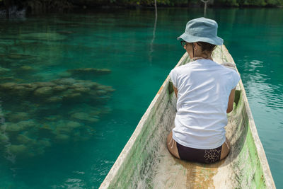 Rear view of woman sailing in rowboat in sea