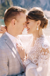 Smiling bridegroom embracing while standing outdoors