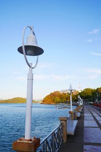 Street light by river against sky