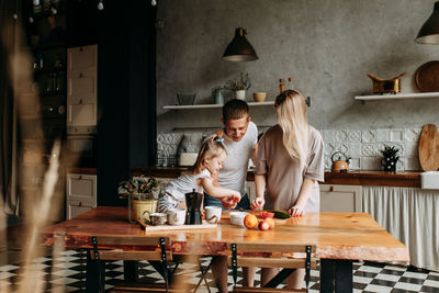 A happy cheerful family with a child is cooking dinner together in the kitchen at home