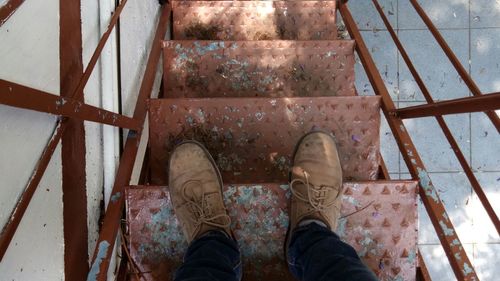 Low section of man wearing shoes standing on metallic steps
