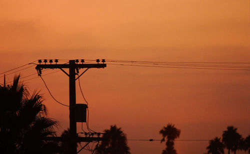 Low angle view of silhouette electricity pylon against sky during sunset