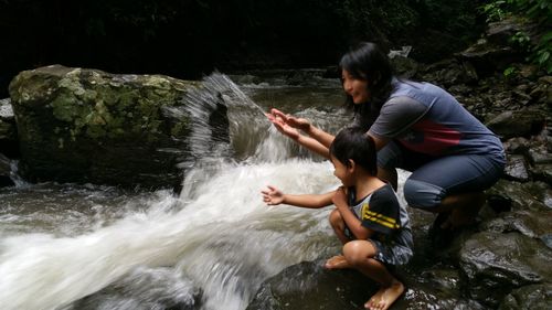 Mother and son splashing water in stream