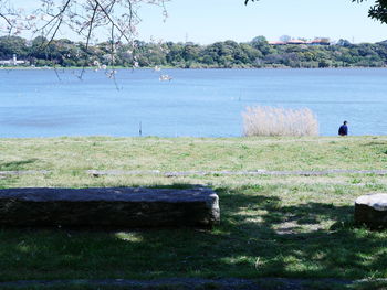 Scenic view of land by lake against sky