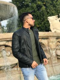 Young man smiling while standing against trees