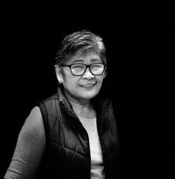 Portrait of senior woman wearing eyeglasses against black background