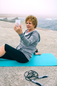 Young woman using phone while sitting on beach