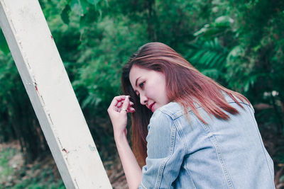 Beautiful young woman standing against plants