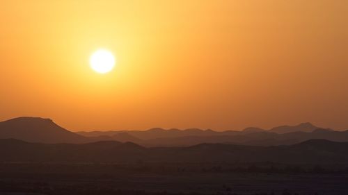 Scenic view of silhouette mountains against orange sky