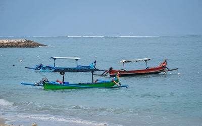 View of fishing boats in sea against clear sky