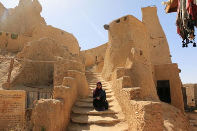 Low angle view of woman sitting at steps