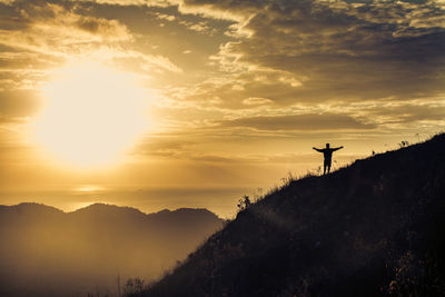 Silhouette person on mountain against sky during sunset