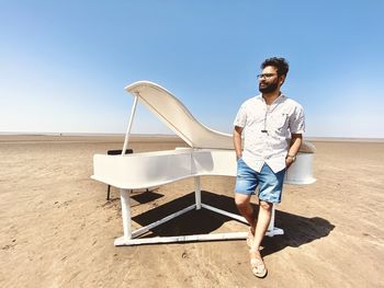 Man standing beside piano. beach and sk