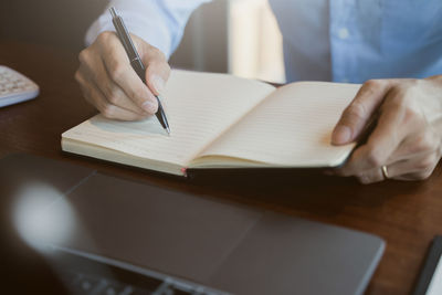 Midsection of man reading book on table