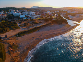 High angle view of sea and buildings against sky at sunset